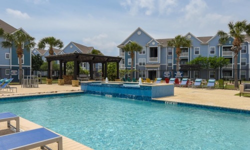 pool with a building in the background at apartments in Corpus Christi.