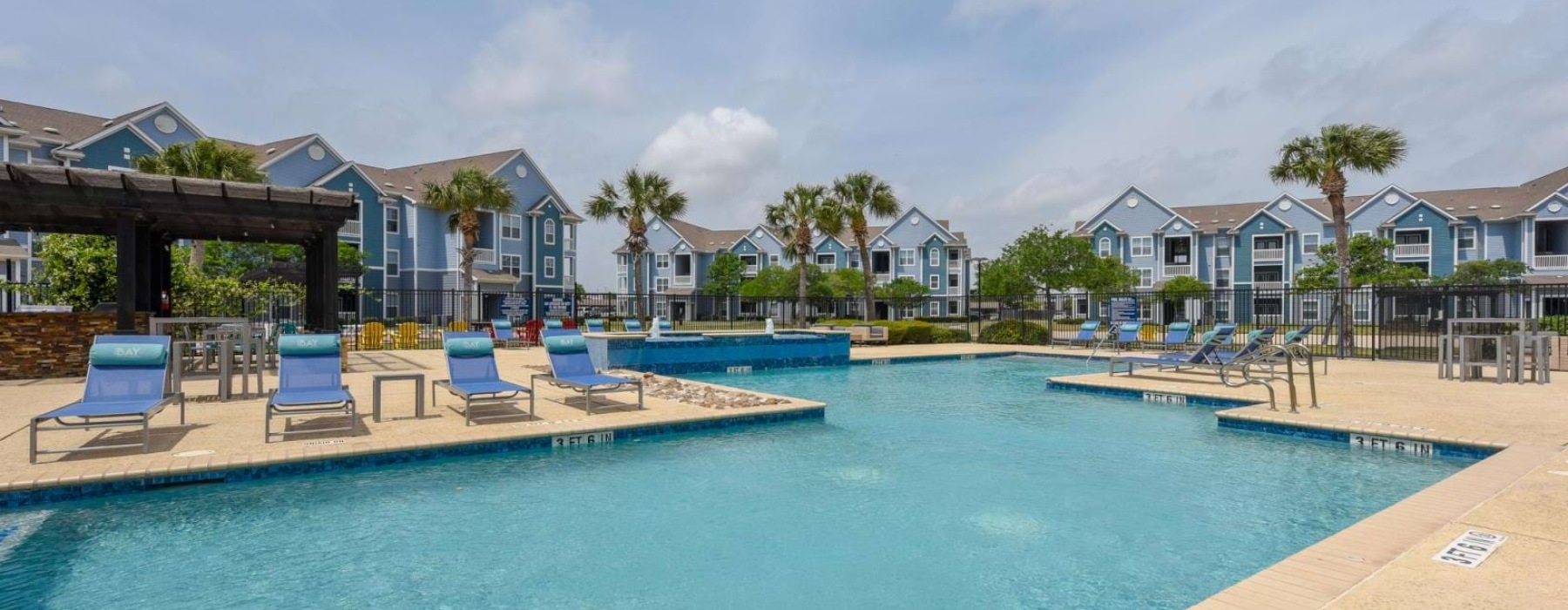 a pool with chairs and tables by it and houses in the background