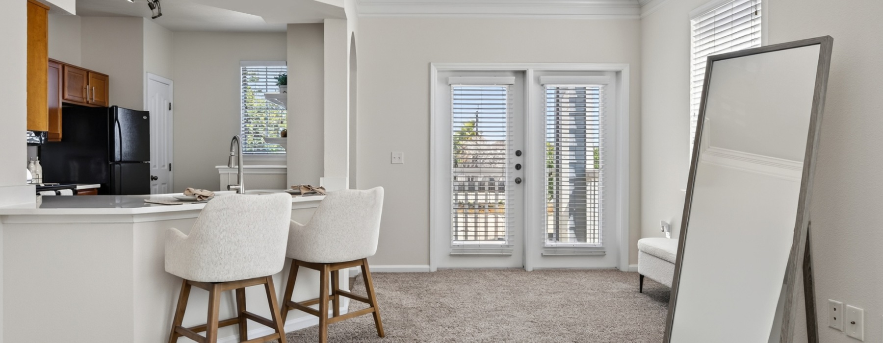 living room with a large mirror and kitchen with chairs